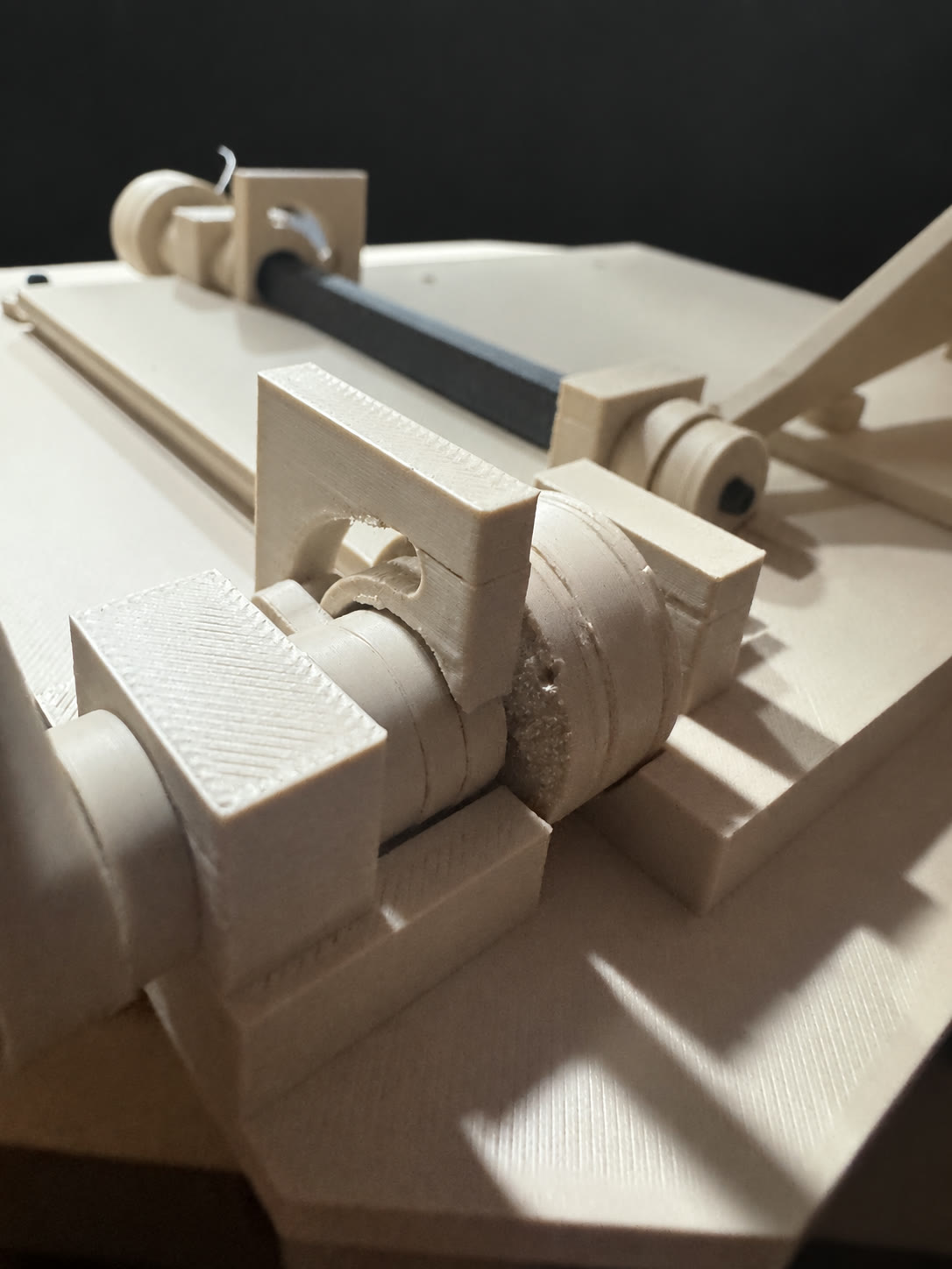 Close view of the printed Easter Tomb cross-shaft and cord drums against a cleaned dark background