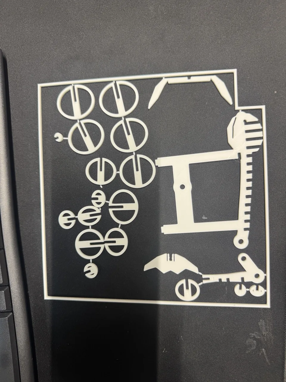 White 3D-printed whale kit parts still attached to a flat frame.