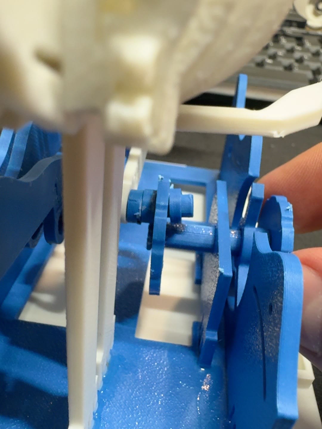 Close view of the blue crank shaft and retaining clip beside the whale wave panels